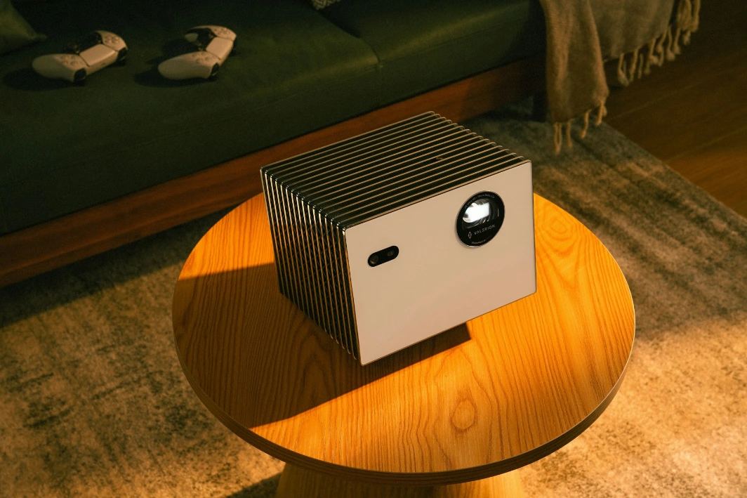 Modern projector sits on a wooden coffee table.